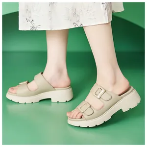 Seitenansicht beige Plateau-Sandalen mit Doppelriemen und Schnallen vor grünem Hintergrund