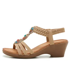 Détail de sandales compensées bohèmes avec perles colorées, strass et brides tissées