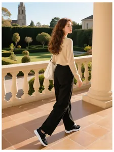 Outdoor shot of stylish beige slim knit top with black wide-leg trousers and sneakers