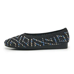 Detail of knitted women flat shoes featuring a black base and blue wavy patterns