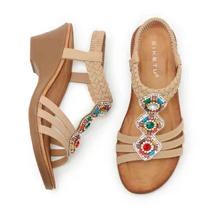 Détail de sandales bohèmes à talons compensés avec strass colorés et semelle bois