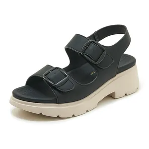 Dettaglio di sandali neri con zeppa, doppie fibbie e spessa suola platform color crema