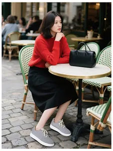 Grey lightweight sneakers styled with a red sweater and black skirt in a street setting