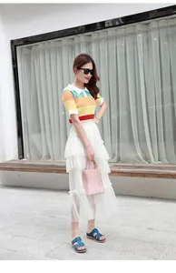 Polo en maille rayée arc-en-ciel avec jupe longue en dentelle blanche et sandales bleues