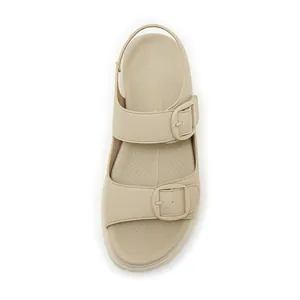 Dettaglio dei sandali beige con zeppa con grande fibbia in metallo e cinturino elastico