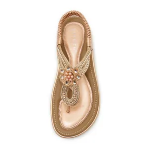 Macro view of rose gold flip-flop sandal featuring rhinestone flower and braided straps