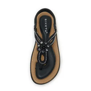 Close-up of black thong sandal featuring intricate rhinestone flower and beaded strap