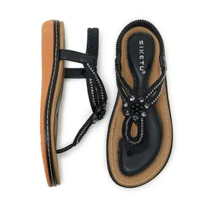 Detail of bohemian black T-strap sandals featuring rhinestone flowers and beaded weaving