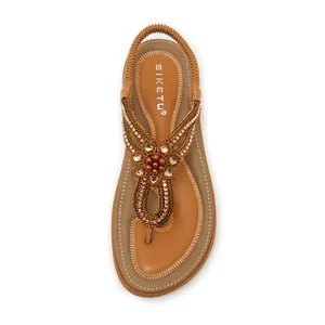 Detail of bohemian rhinestone flower embellishment on brown braided wedge sandals