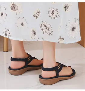 Nahaufnahme dunkelblauer Keilsandaletten mit elastischen Riemen zum Sommerkleid mit Blumen