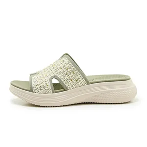 Macro-opname van groene geweven sleehak slippers met strassteentjes en H-vormig detail