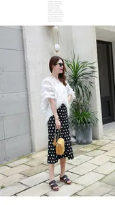 Look extérieur avec sandales noires à brides, jupe à pois et haut blanc élégant