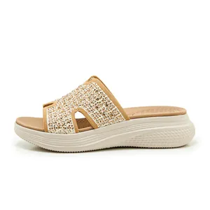 Detailopname van amberkleurige strass-steentjes op abrikooskleurige sandalen