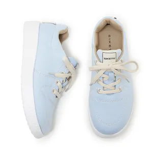 Detail of light blue canvas sneakers with thick white anti-slip rubber soles and white laces