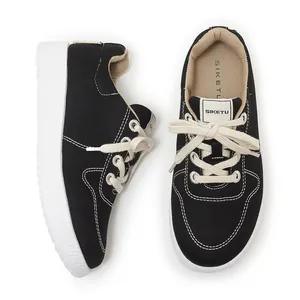 Top view of black canvas sneakers with white platform rubber soles and contrast stitching