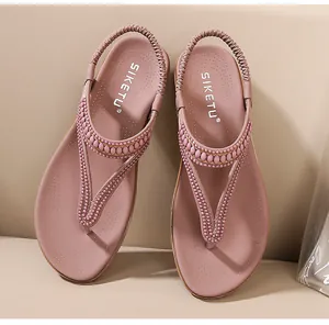 Nahaufnahme der rosa T-Strap-Sandalen mit Perlenverzierung und elastischem Fersenriemen