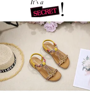 Detail of yellow Bohemian flat sandals with woven straps and rhinestone embellishments