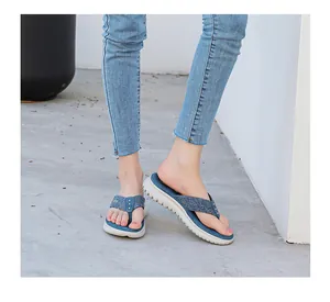 Detail view of navy denim flip-flops with silver rivets and white platform sole on a model