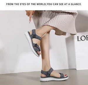 Detail of dark grey woven straps and thick white non-slip sole on women's wedge sandals