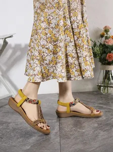 Detailed view of yellow bohemian wedge sandals with colorful beadwork and elastic strap