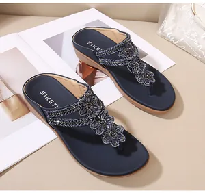 Detalle de sandalias con cuña, flores de cuentas azul marino y plantilla acolchada SIKETI