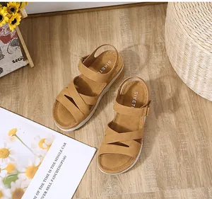 Dettaglio dei sandali platform kaki con cinturini incrociati su un pavimento in legno