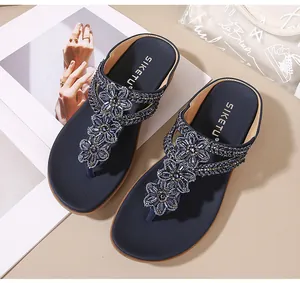 Detalle de sandalias de cuña azul marino con bordados florales y pedrería estilo bohemio