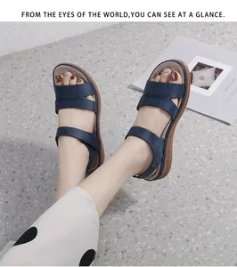 Détail de sandales plates bleu marine avec brides à points croisés sur marbre