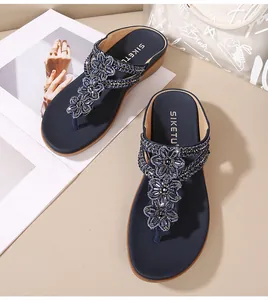 Detalle macro de sandalias con cuña azul marino con flores de cuentas y pedrería brillante