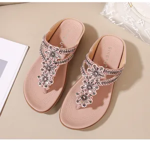 Detalle de sandalias de cuña rosa con decoraciones florales de diamantes de imitación