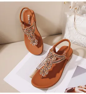 Vue détaillée des motifs de fleurs perlées et strass sur sandales bohèmes marron