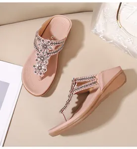 Detalle de flores de pedrería en sandalias de cuña rosa con suela de masaje suave