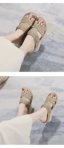 Dettaglio di sandali beige con zeppa con cinturini incrociati e trafori decorativi