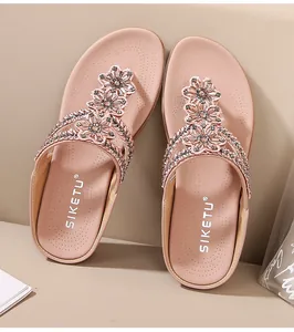 Detalle de sandalias de cuña rosas con flores de diamantes de imitación brillantes