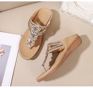 Detalle de sandalias de cuña con flores de cuentas y pedrería sobre suela cómoda