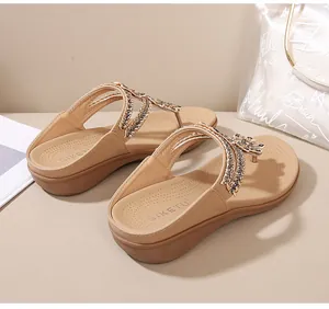 Primer plano de los adornos de diamantes de imitación en las sandalias de cuña beige