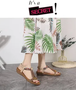 Detail of bohemian T-strap sandals featuring colorful woven straps and vintage metal flowers