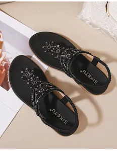 Détail de sandales noires d'été avec broderies de fleurs en strass et bride élastique confortable