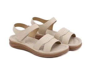 Détail de sandales à talons compensés beige avec lanières croisées et coutures blanches en X