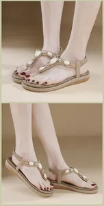 Détail de sandales à bride en T beige avec pierres ovales blanches et accents strass
