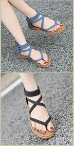 Primer plano de sandalias romanas planas para mujer con tiras cruzadas y hebilla fina