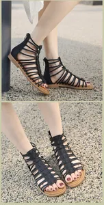 On-foot view of black snake-textured Roman sandals with flat soles and cross straps