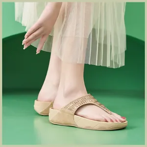Detalle de sandalias de plataforma beige con correas de pedrería en pies de modelo