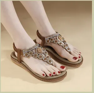 Detailansicht brauner flacher Zehentrenner-Sandalen mit aufwendigen Strass-Blumenverzierung