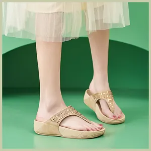 Detalle de sandalias de plataforma beige con tiras de pedrería dorada brillante