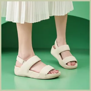 Vista laterale di sandali platform crema con chiusura a strappo e suole spesse su verde
