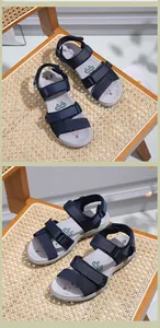 Détail de sandales de sport bleu foncé avec brides velcro réglables sur une chaise en rotin