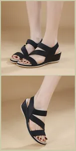 Dettaglio dei sandali con zeppa neri con cinturini elastici e suola beige strutturata
