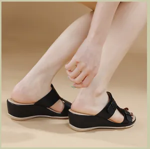 Detalle de sandalias de cuña negras con textura de cuero y hebilla de metal en la tira