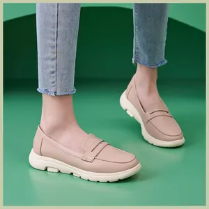 Detail von nudefarbenen Leder-Loafers mit weißer dicker Sohle an einem Model vor grün